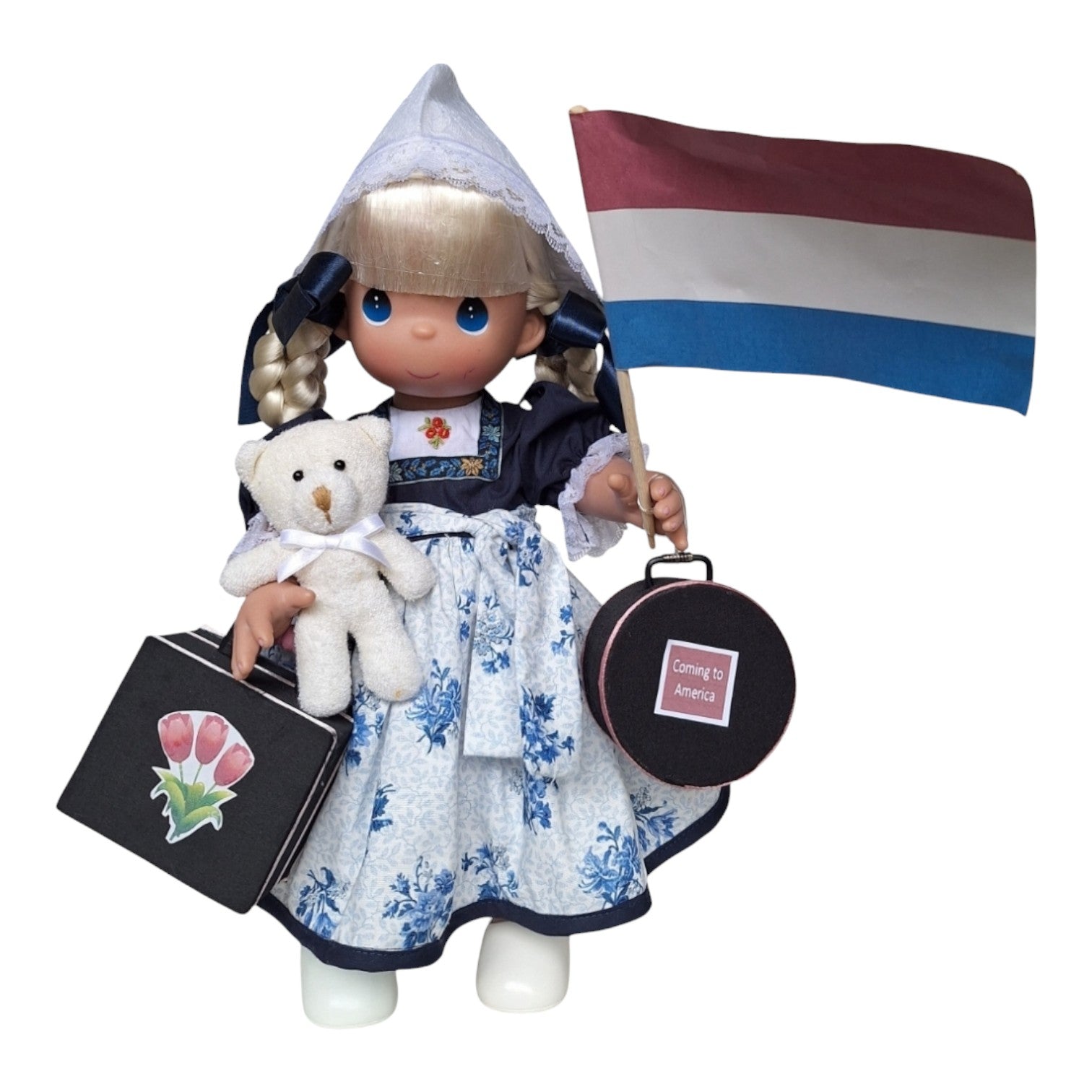 The Doll Maker 16-inch Holland vinyl doll wearing traditional Dutch dress with a teddy bear, suitcases, and flag.