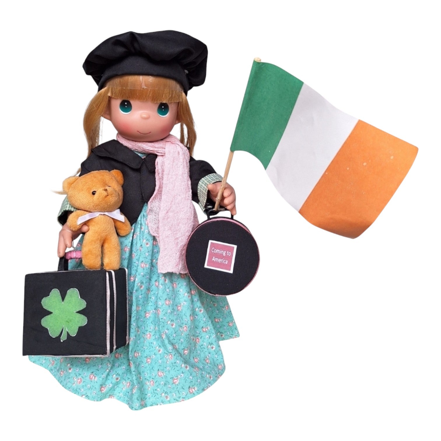The Doll Maker 16-inch Ireland vinyl doll wearing a black hat and floral dress, holding a bear and Irish flag.