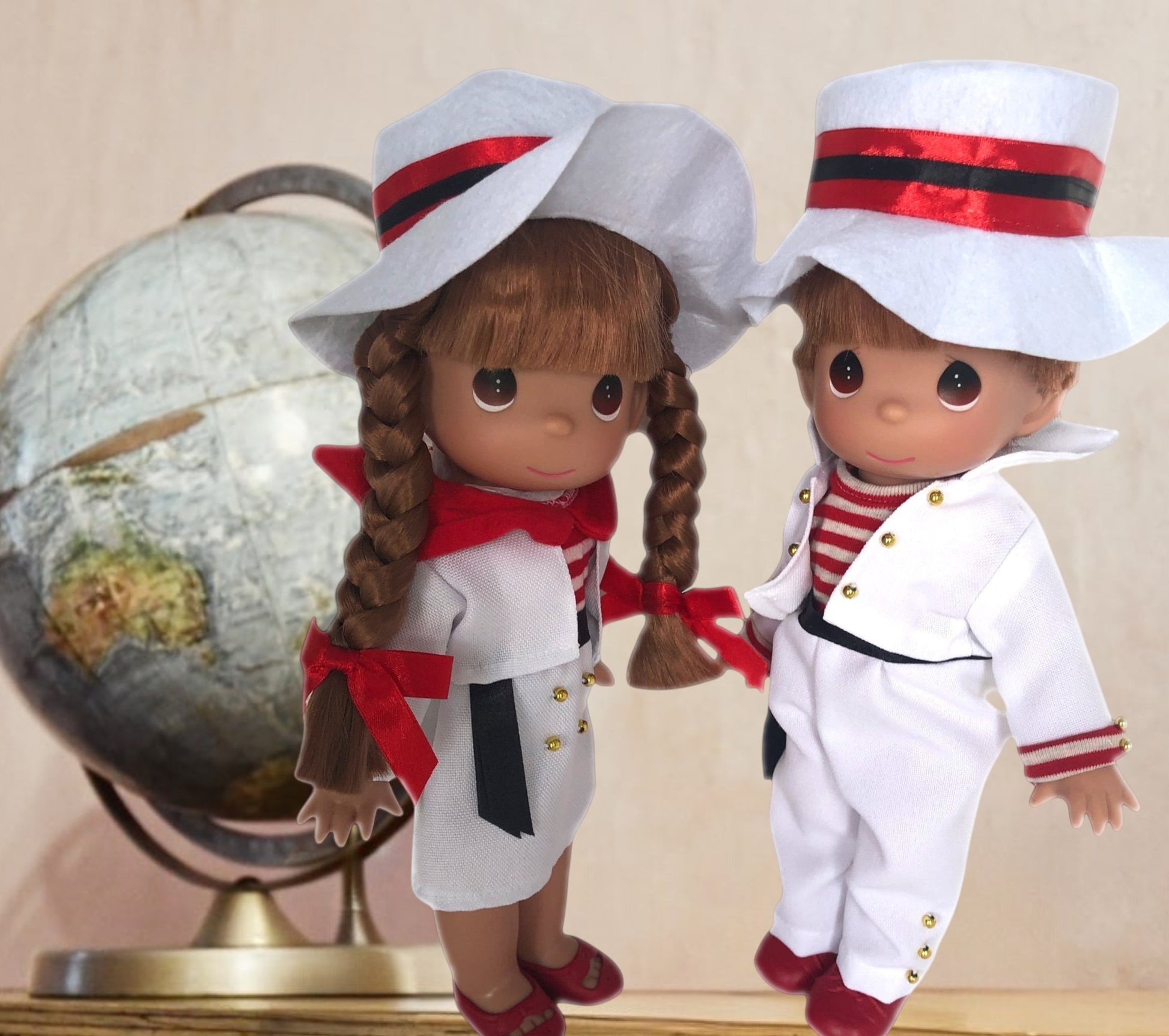 The Doll Maker 12-inch Italy boy and girl dolls wearing traditional white outfits with red accents and matching hats.