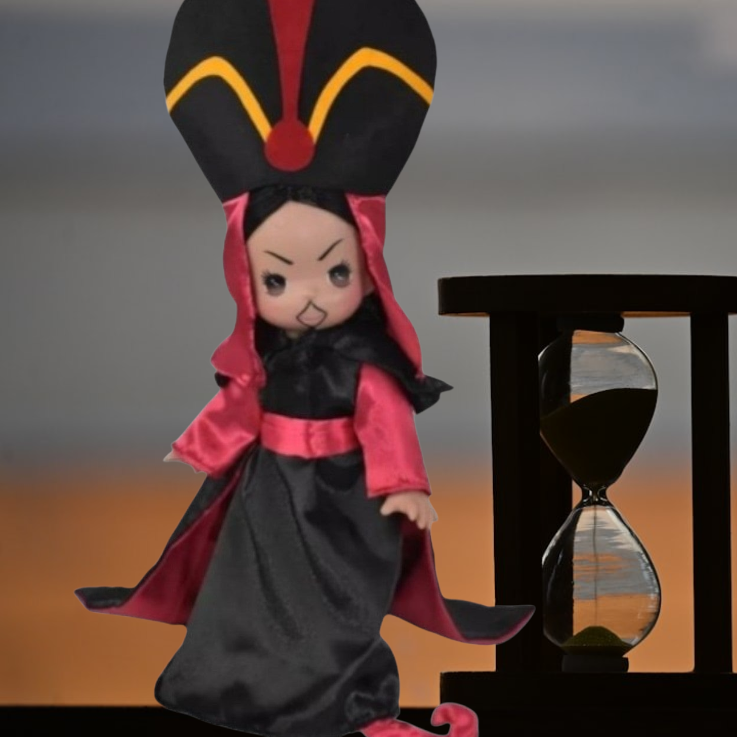 The Doll Maker 12-inch Jafar vinyl doll wearing signature black and red robes with a tall headpiece next to hourglass.