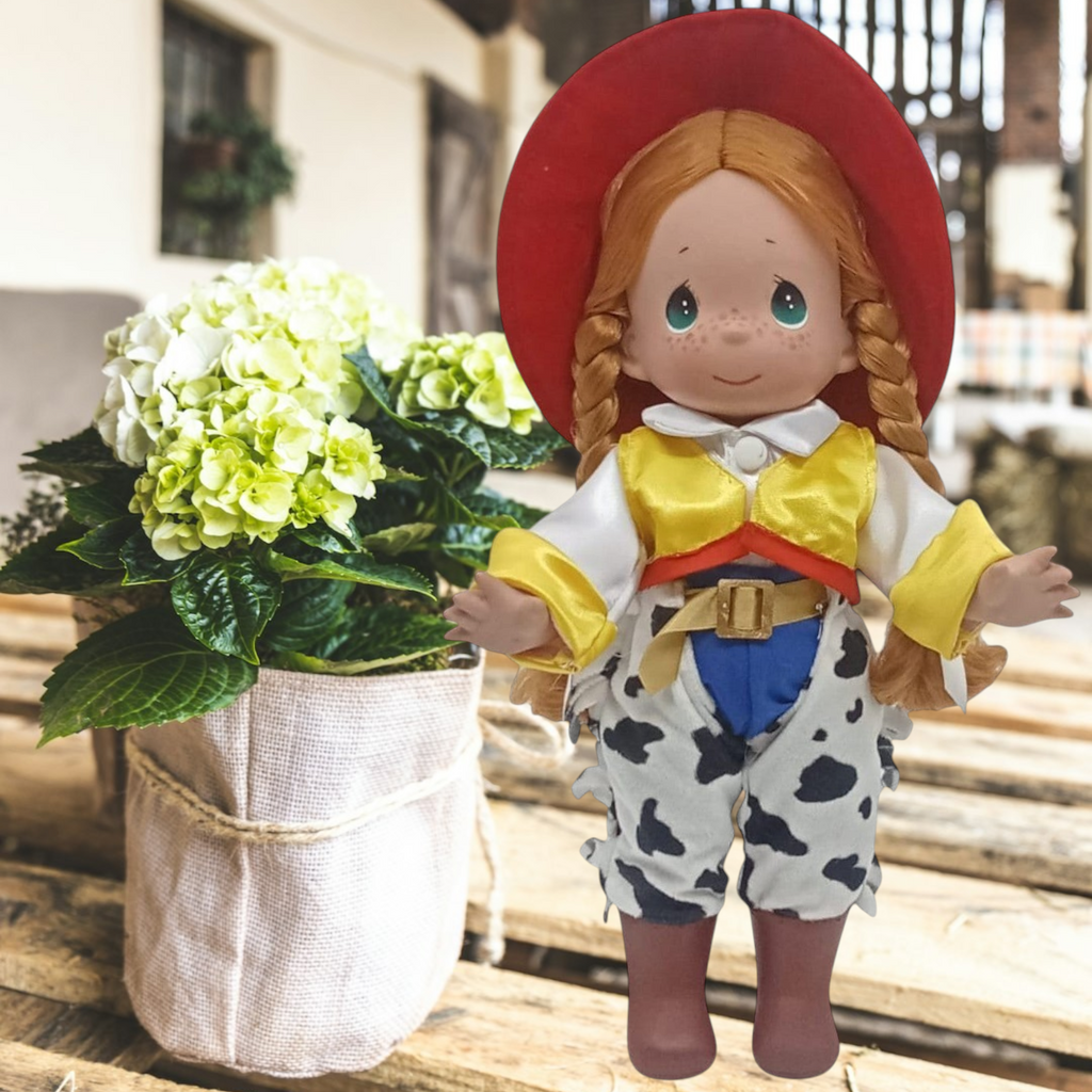 The Doll Maker 12-inch Jessie cowgirl doll from Toy Story with red hat, yellow vest, and cow-print chaps on a table.
