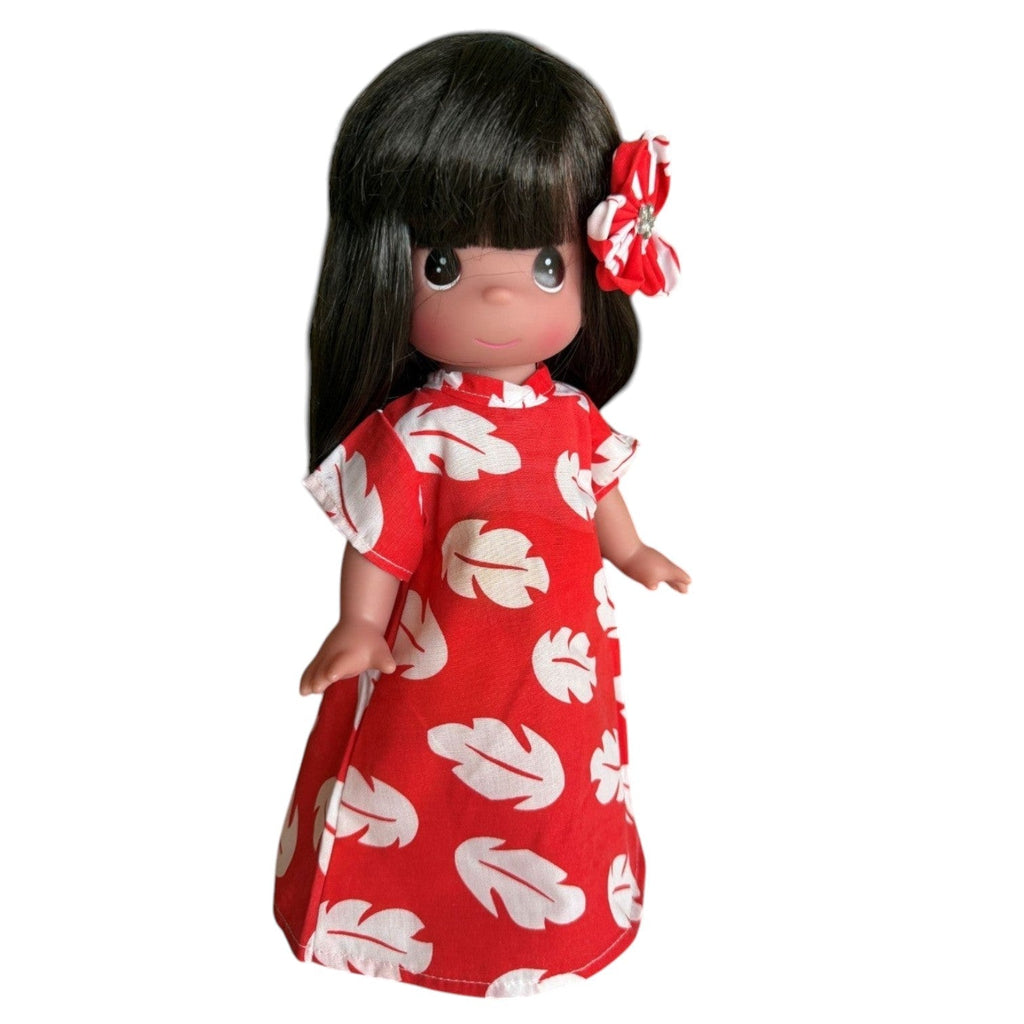 The Doll Maker 12-inch Lilo vinyl doll wearing a red and white leaf-print dress with a matching hair flower.