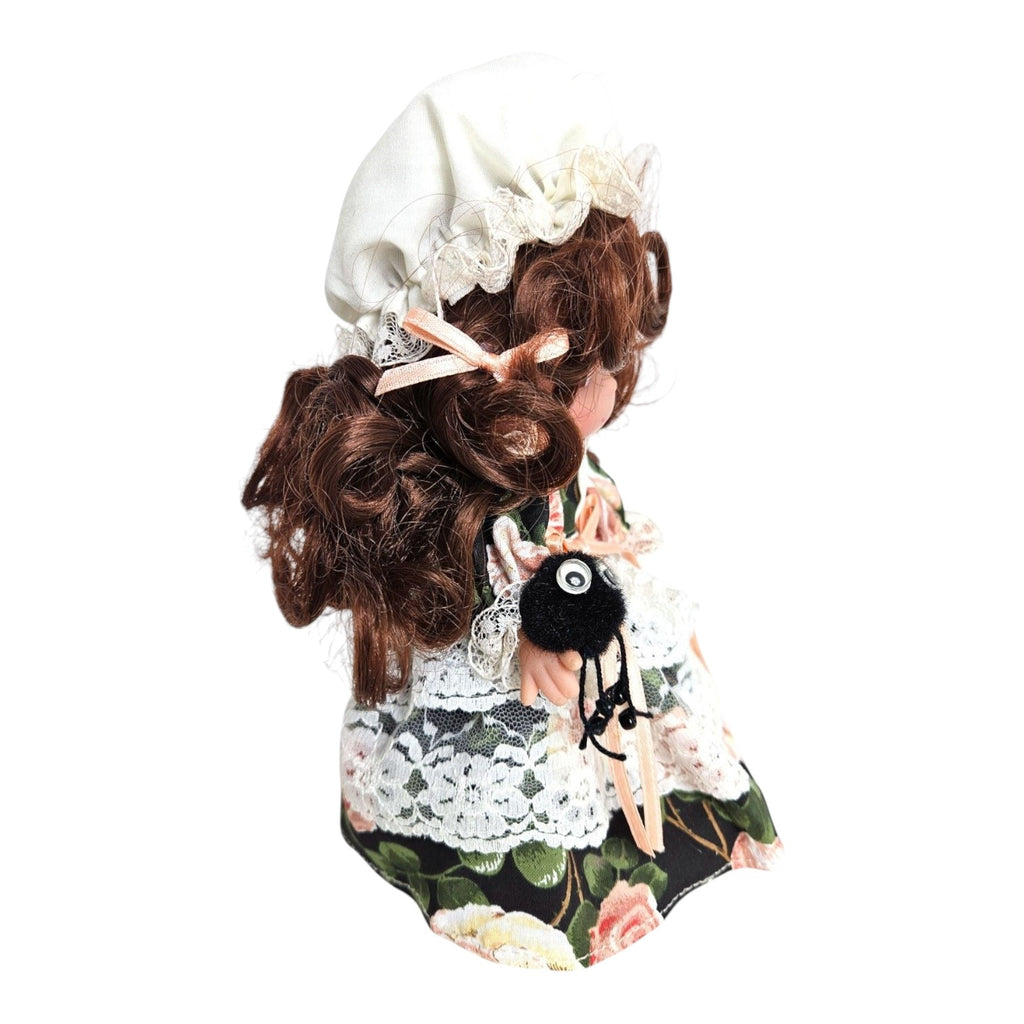 The Doll Maker 7-inch Little Miss Muffet vinyl doll with brunette hair, wearing a floral dress and holding a spider.