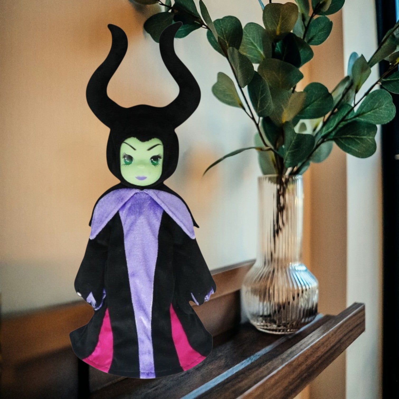 The Doll Maker 12-inch Maleficent collectible doll with iconic black horns, green skin, and purple and black robes.