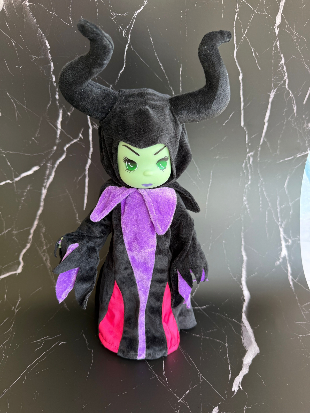 The Doll Maker 12-inch Maleficent collectible doll featuring a black horned headpiece and purple and pink velvet gown.