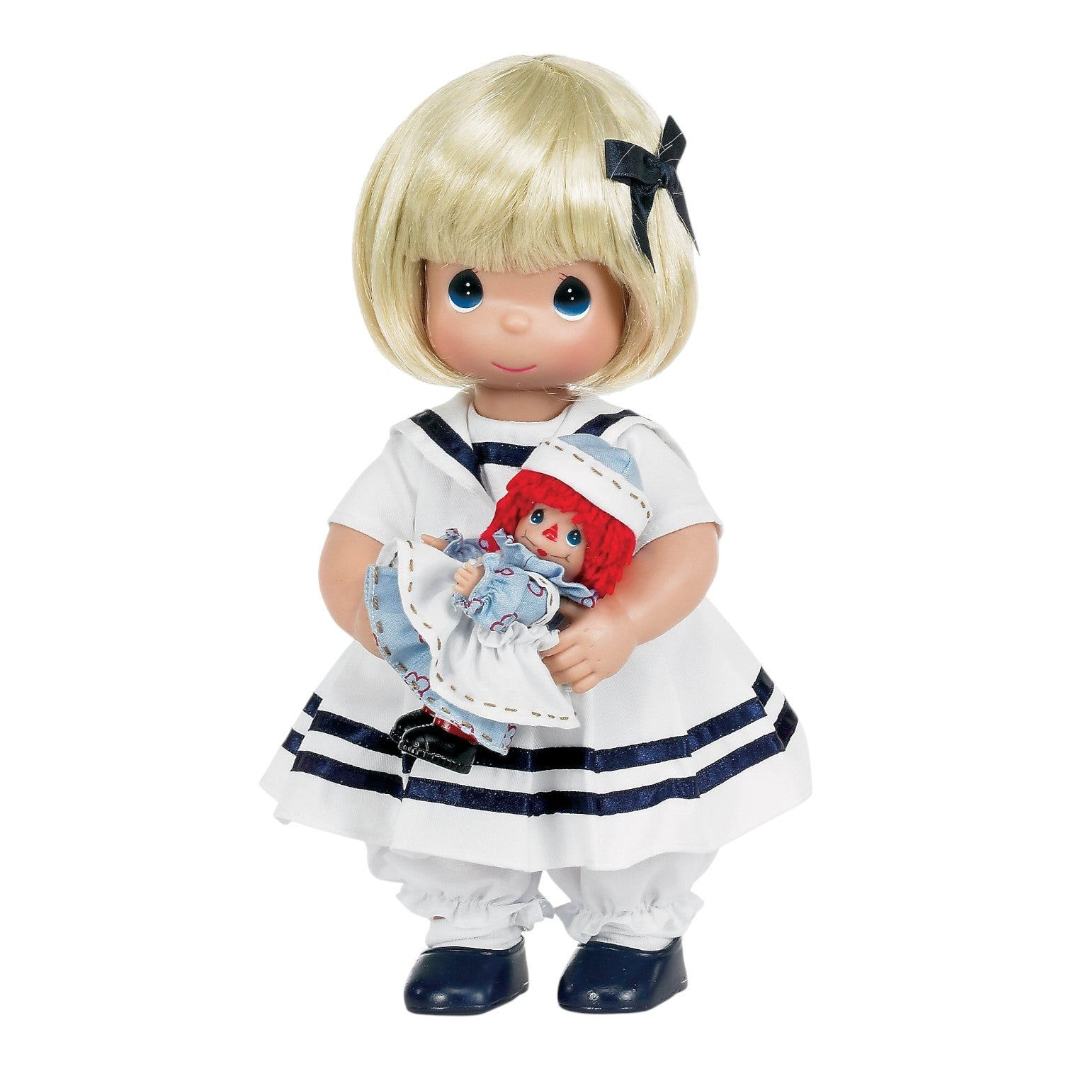 The Doll Maker Marcella vinyl doll with blonde hair wearing a white sailor dress, holding a small Raggedy Ann doll.