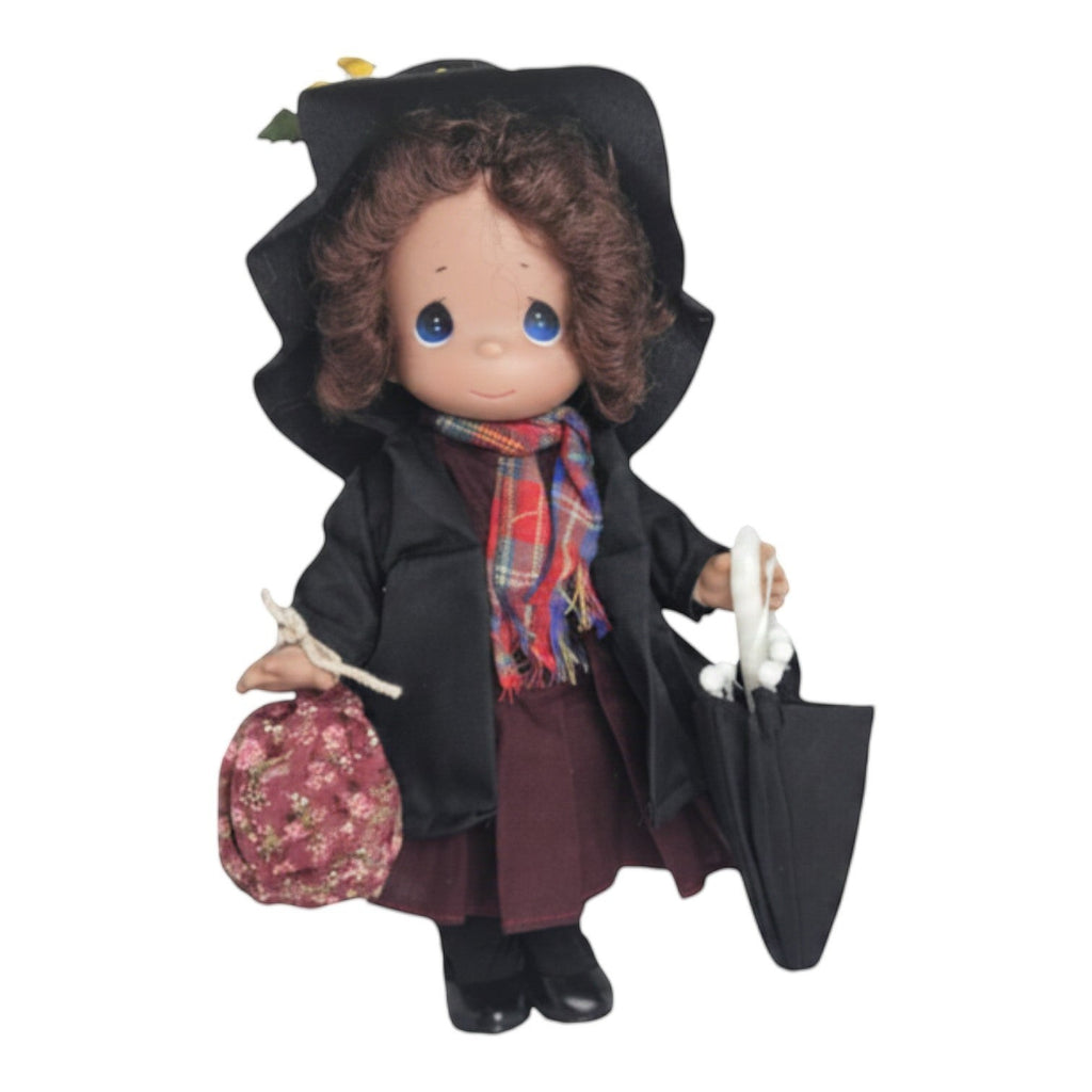 The Doll Maker 12-inch Mary Poppins chimney sweep doll wearing a black coat, hat, and plaid scarf with a floral bag.