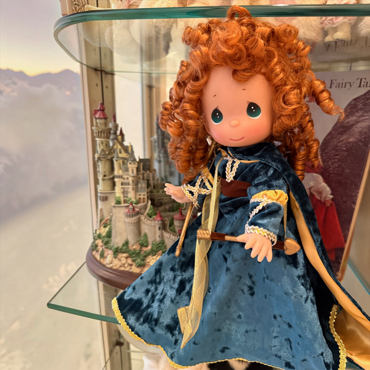 The Doll Maker Merida 12-inch vinyl doll from Brave featuring untamed red hair and a detailed dark blue velvet gown.