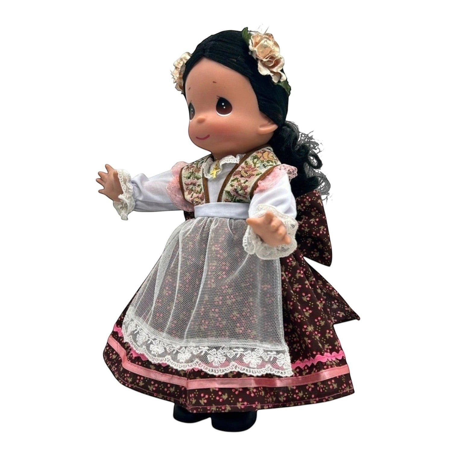 The Doll Maker 12-inch Mexico doll wearing a traditional floral dress, white apron, and flower hair accessory.