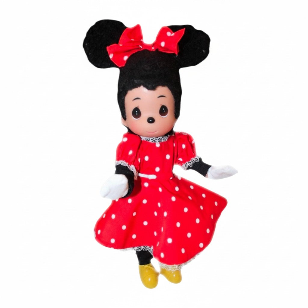 The Doll Maker 12-inch Minnie Mouse vinyl doll wearing a red polka dot dress with a matching bow and yellow shoes.