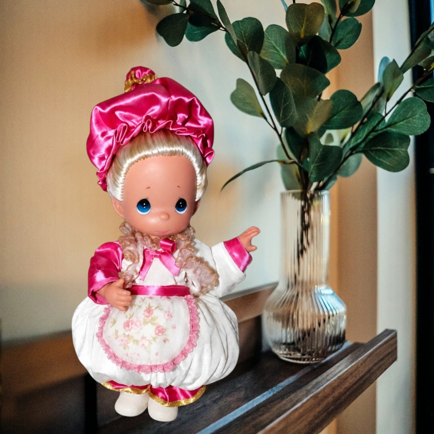 The Doll Maker 12-inch Mrs. Potts collectible doll wearing a white dress with a pink floral apron and satin bonnet.