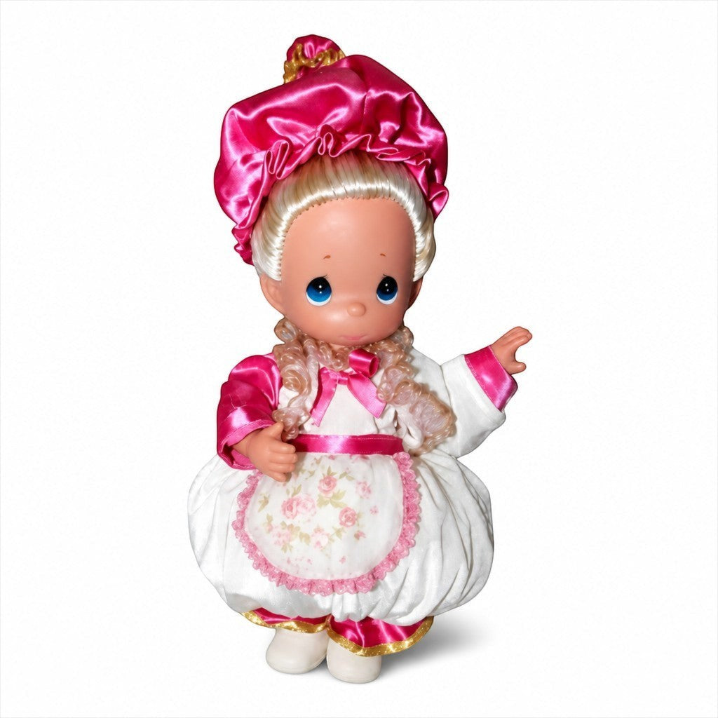 The Doll Maker 12-inch Mrs. Potts doll wearing a white dress with pink floral apron and matching pink satin bonnet.