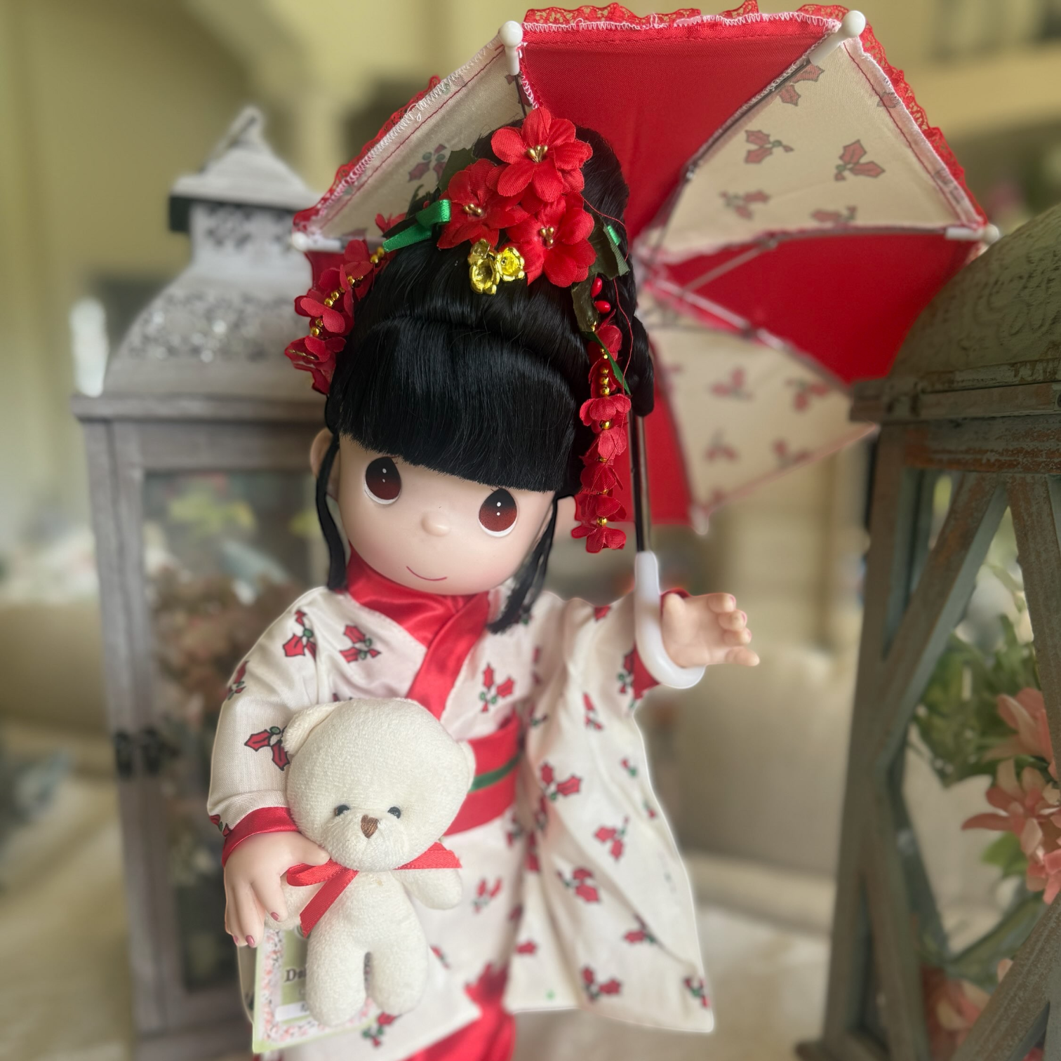 The Doll Maker 16-inch Nodoka doll in a Christmas kimono holding a teddy bear and red umbrella with a doll stand