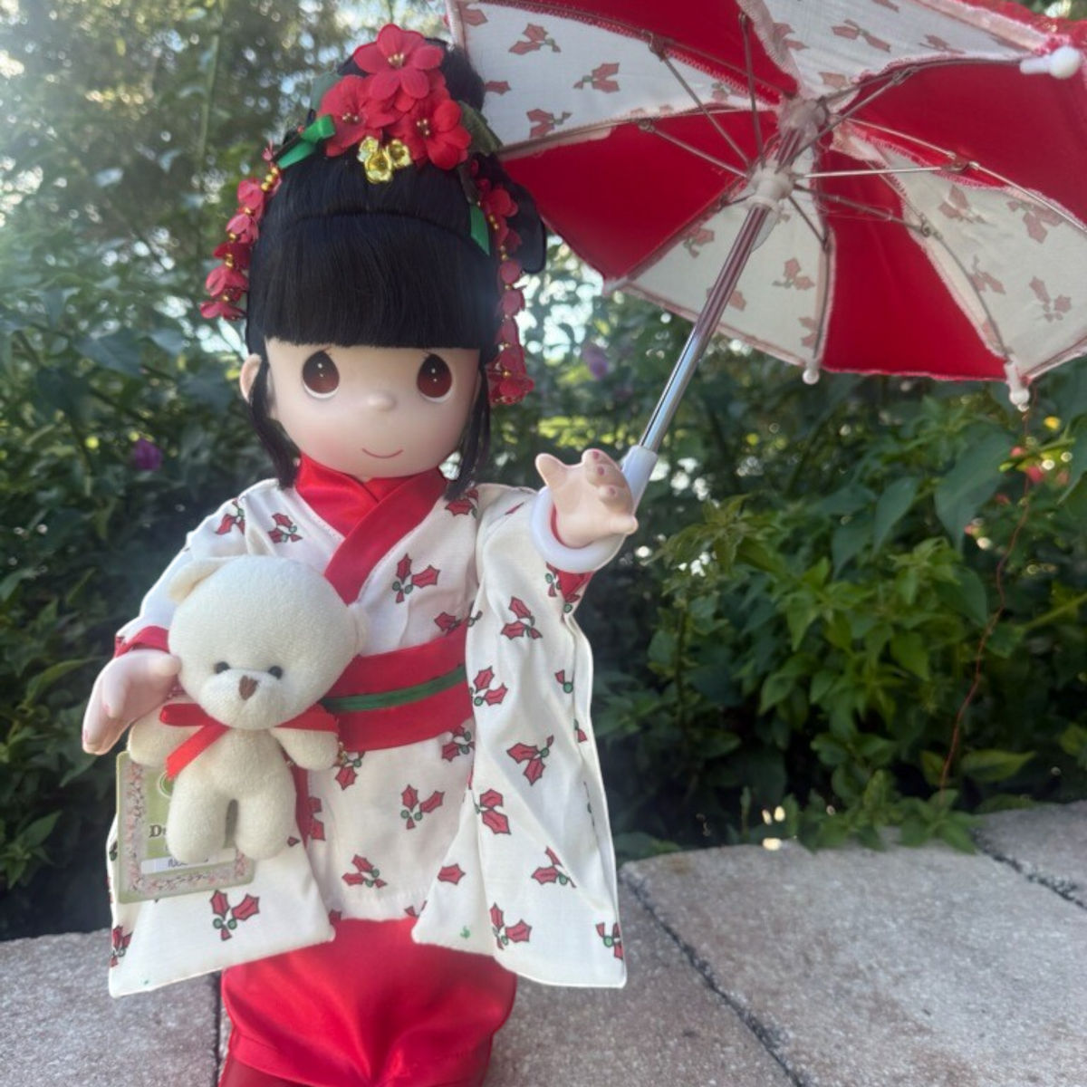 The Doll Maker 16-inch Nodoka Japanese Christmas doll wearing a holly-print kimono with a matching parasol and bear.
