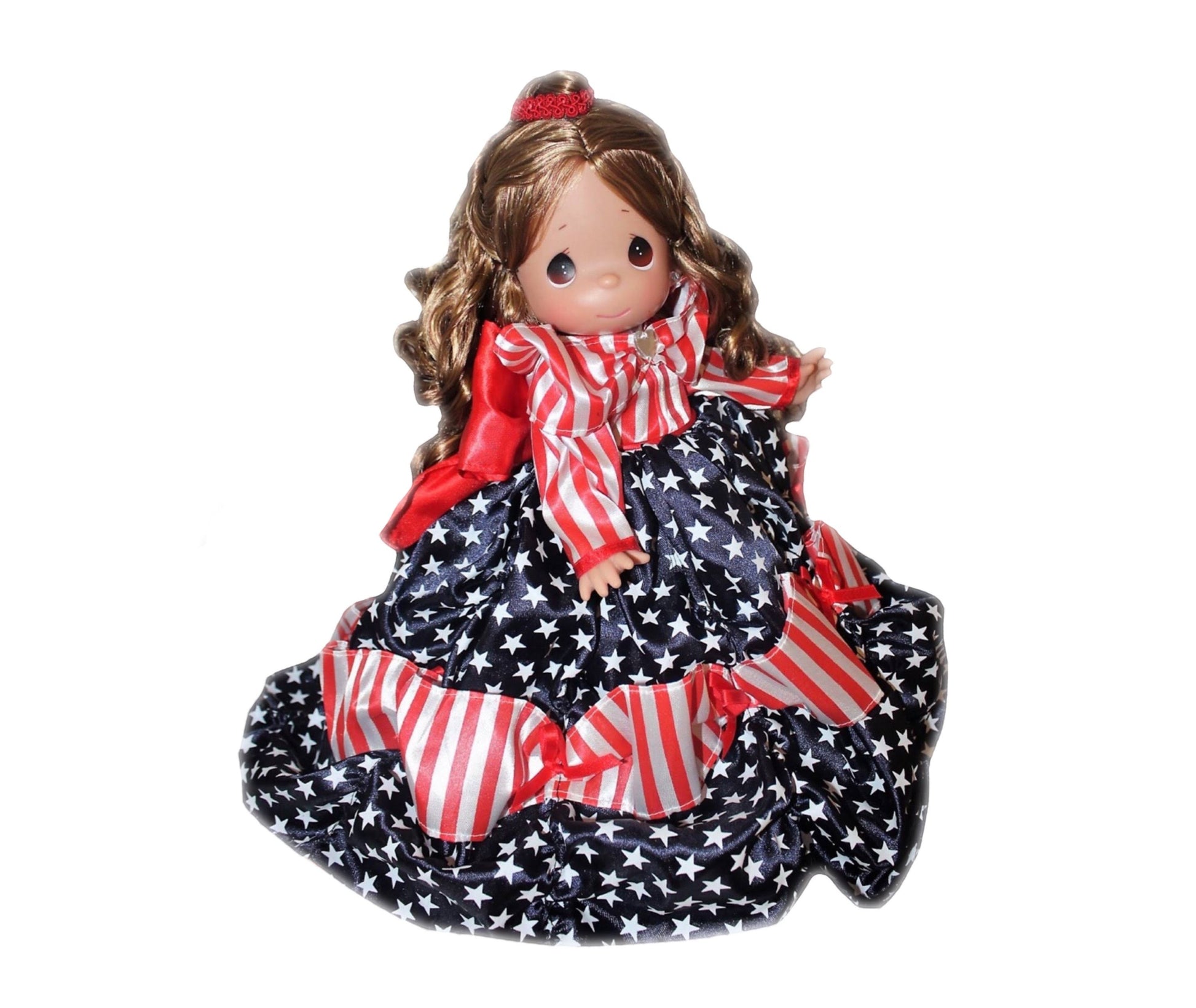 The Doll Maker 12-inch Patriotic Belle doll wearing a red, white, and blue star-patterned gown with striped ruffles.