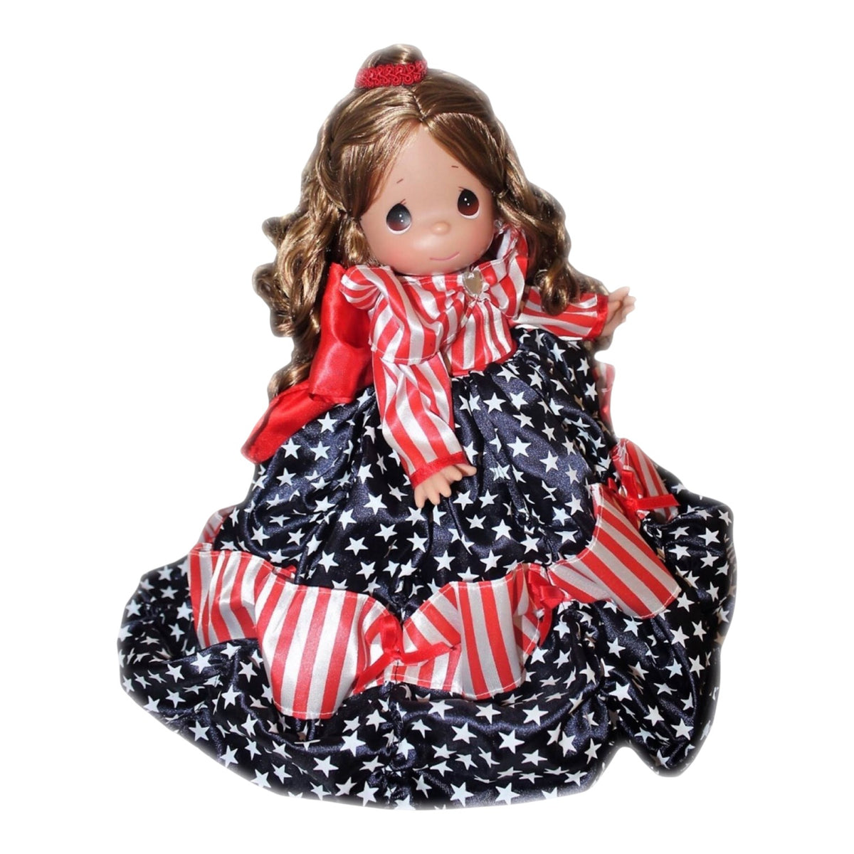 The Doll Maker 12-inch Patriotic Belle doll wearing a red, white, and blue star-patterned gown with striped accents.