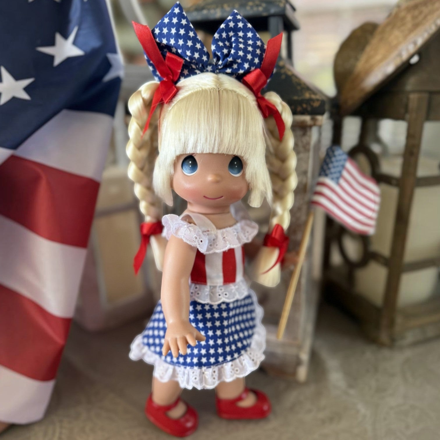 The Doll Maker 12-inch Happy Birthday America doll with blonde braids, wearing a patriotic red, white, and blue dress.