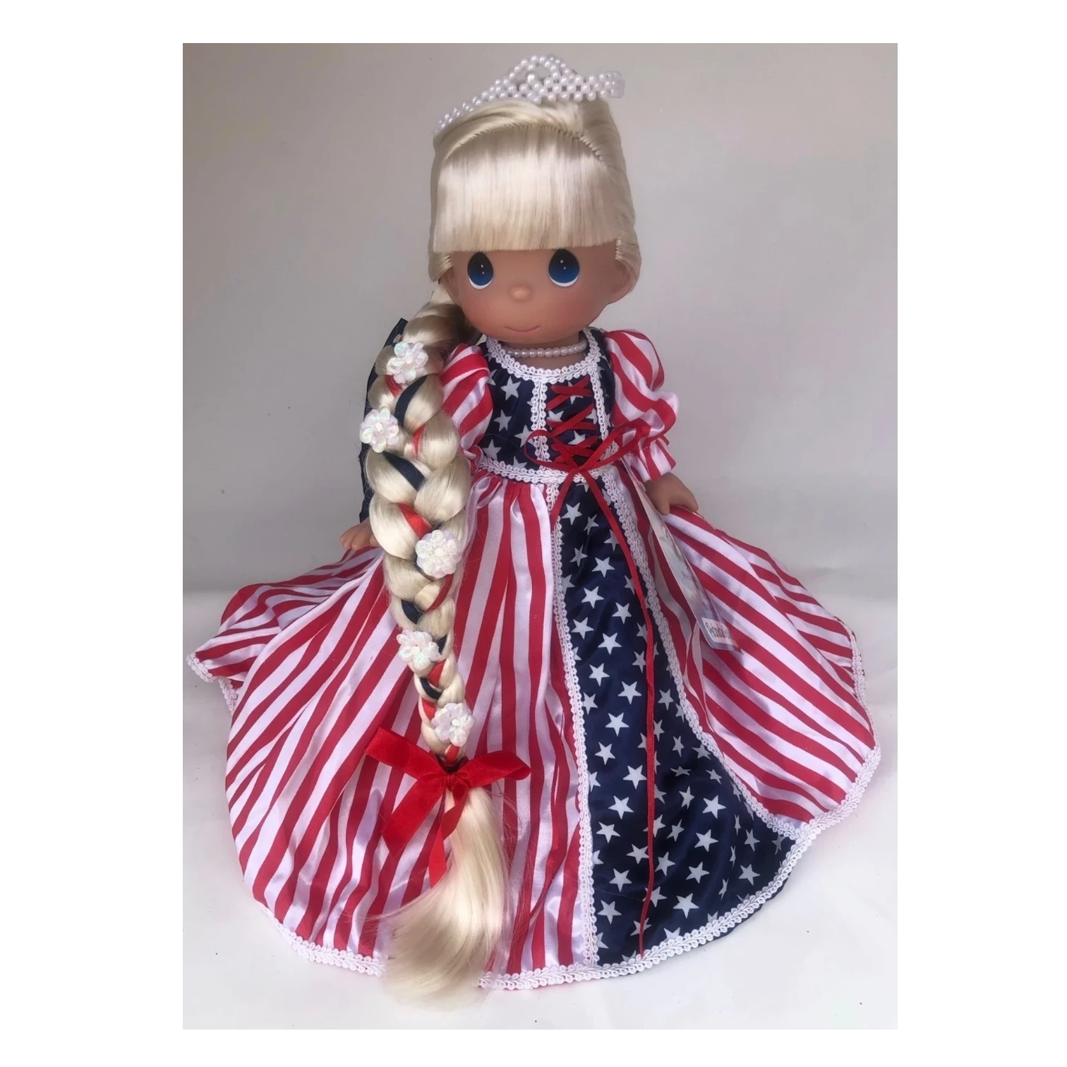 The Doll Maker 12-inch Patriotic Rapunzel doll with long blonde braided hair and a red, white, and blue star dress.