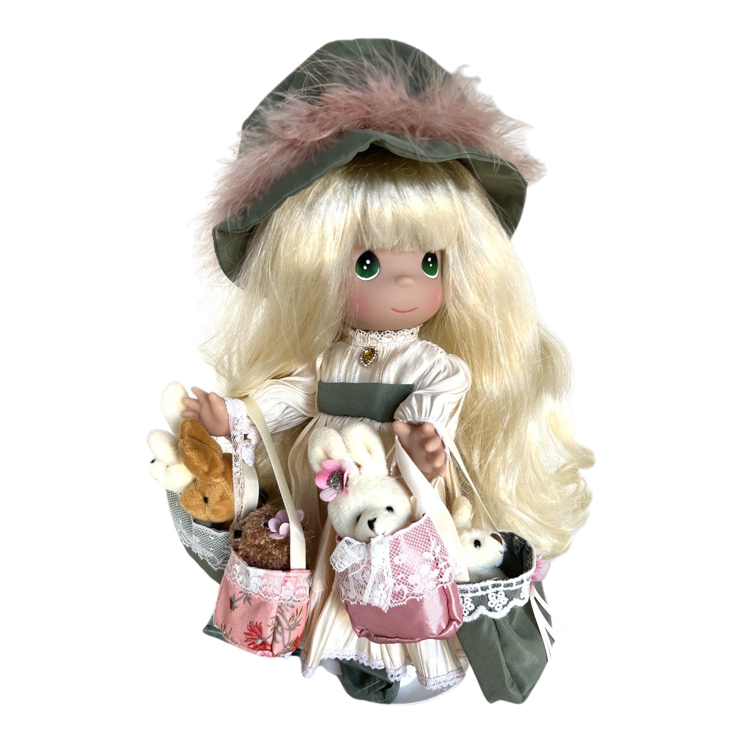 The Doll Maker 12-inch Precious Moments vinyl doll wearing a green hat and dress, carrying plush animals in bags.