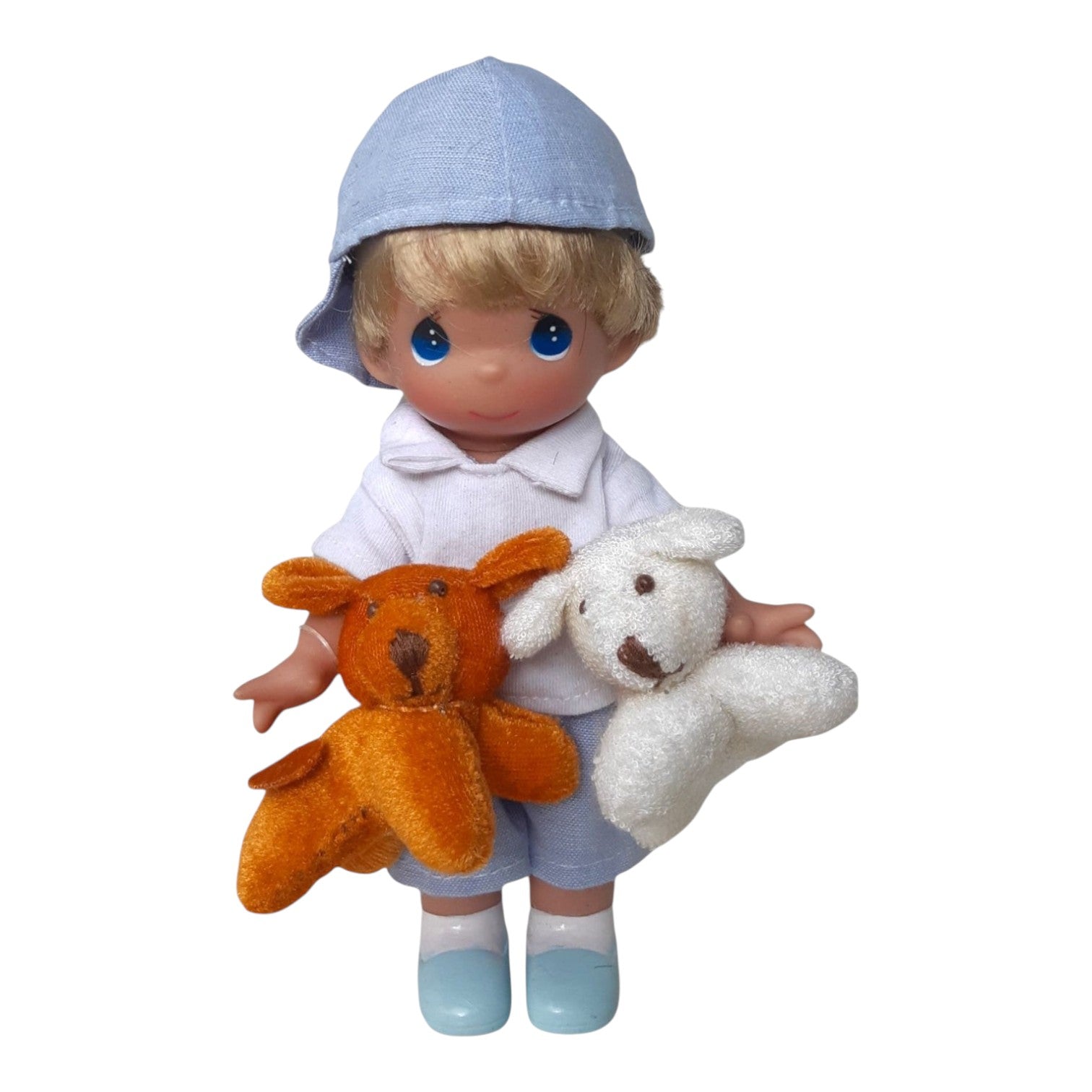 The Doll Maker 7-inch Puppy Dog Tails vinyl doll wearing a blue cap, white shirt, and blue shorts with two plush dogs.
