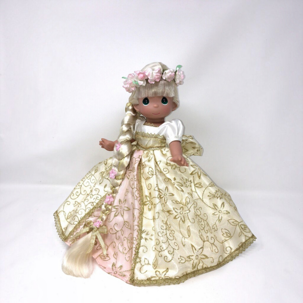 The Doll Maker 12-inch Rapunzel doll wearing a cream and pink floral gown with a long braided hair and flower crown.