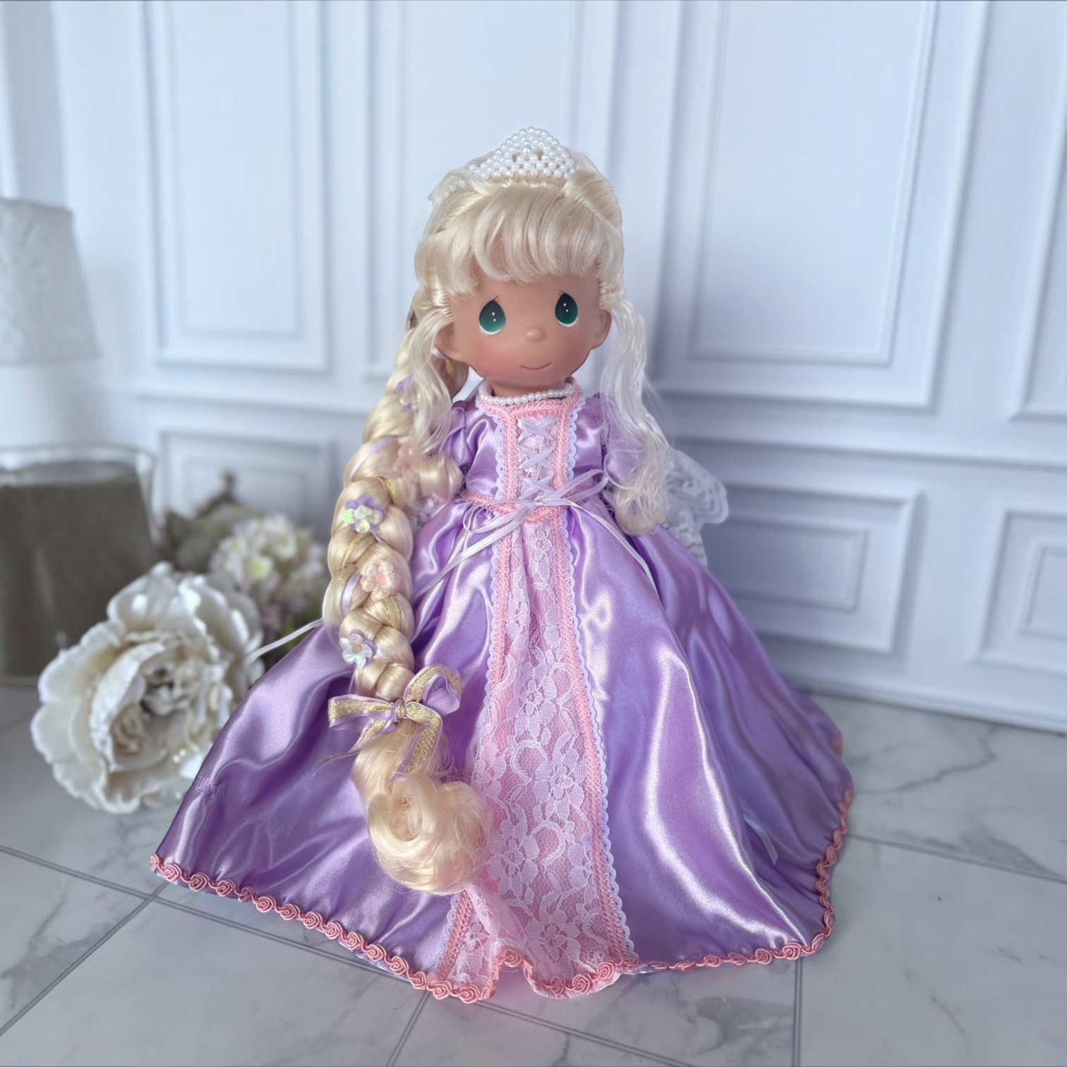 The Doll Maker 12-inch Rapunzel doll wearing a purple satin gown with lace trim and a pearl tiara