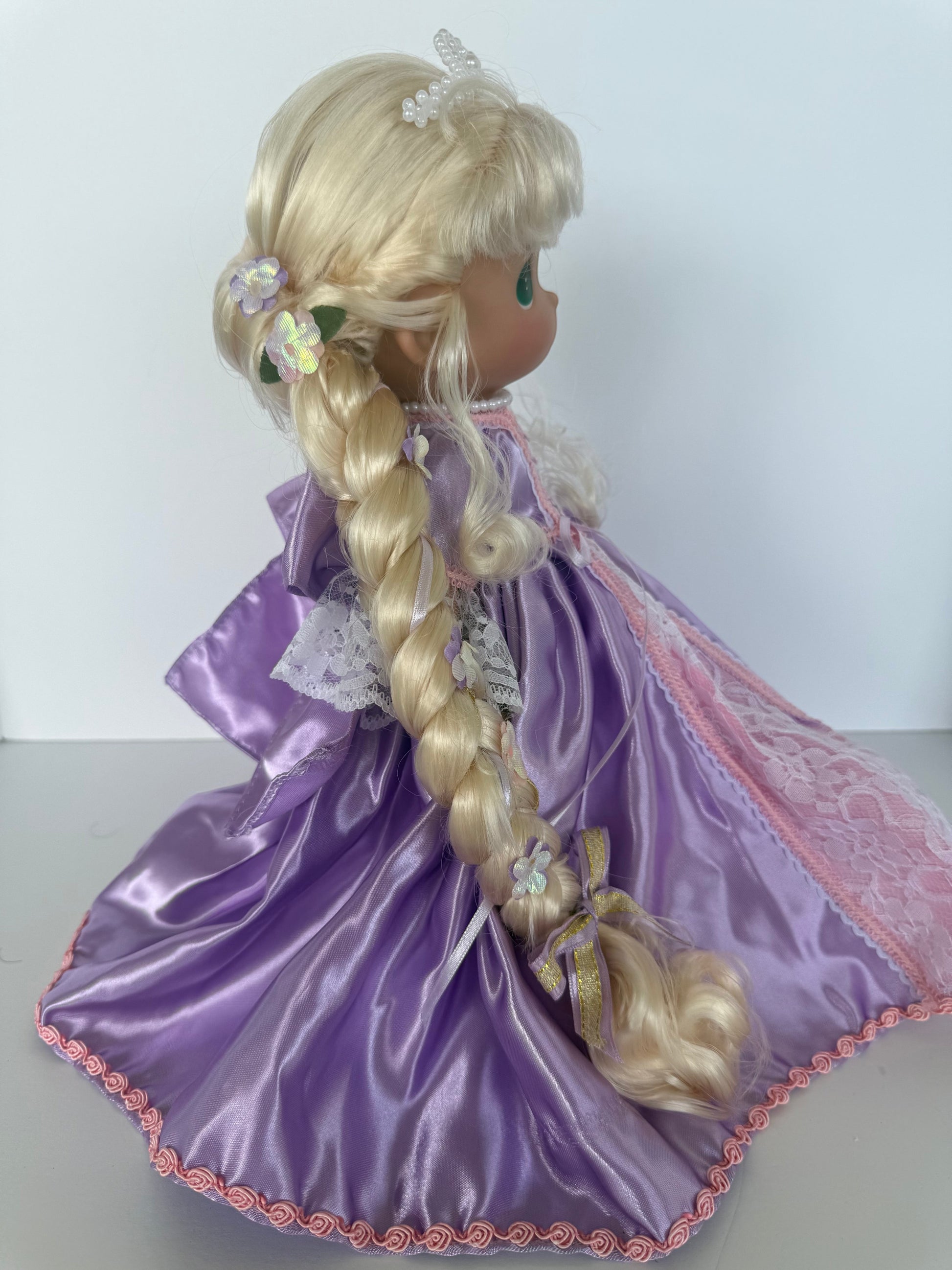 The Doll Maker 12-inch Rapunzel doll with long blonde braided hair and a purple satin gown with lace detail.