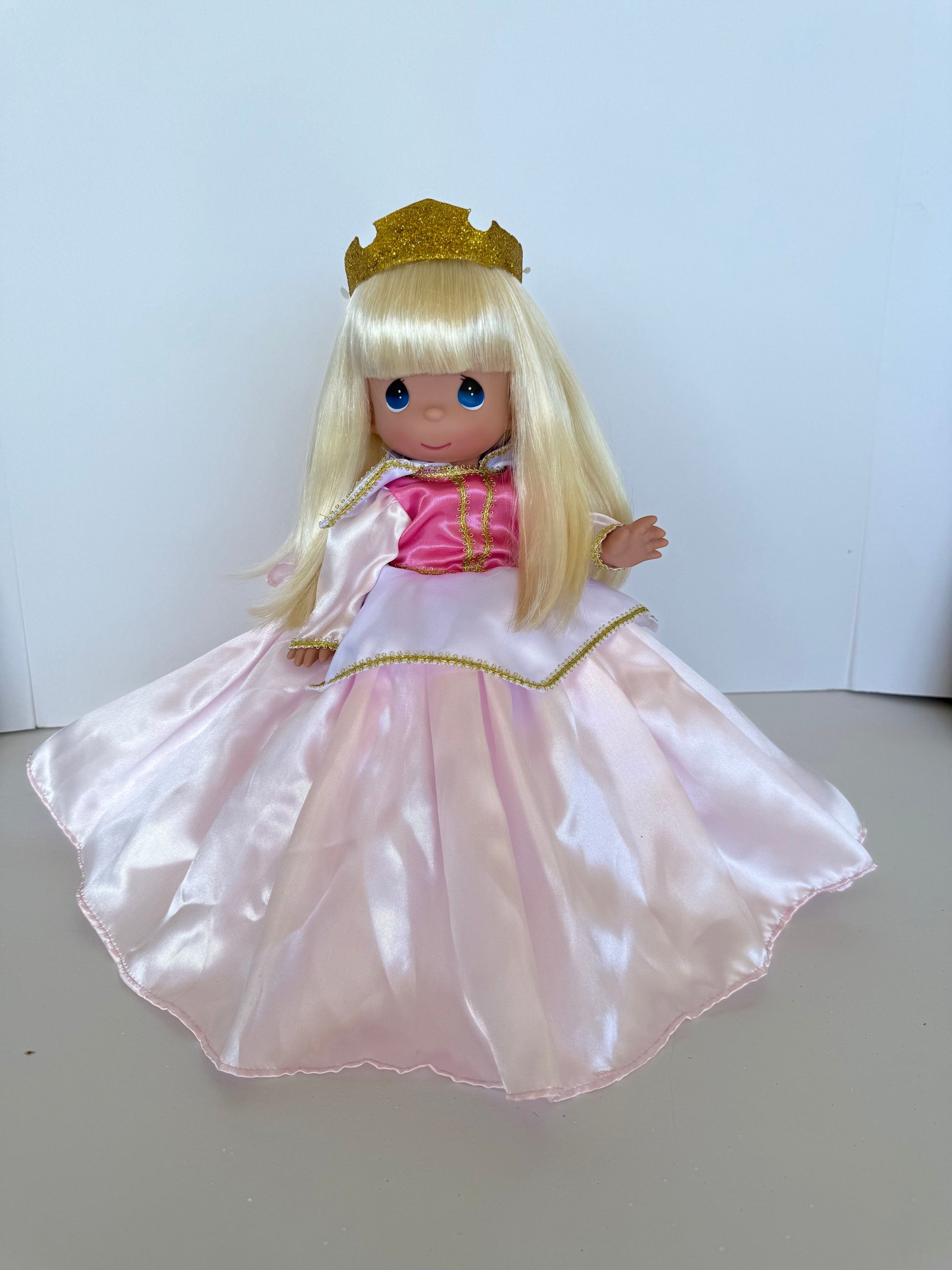 The Doll Maker 12-inch Sleeping Beauty doll with blonde hair, gold crown, and a satin pink and white princess dress.