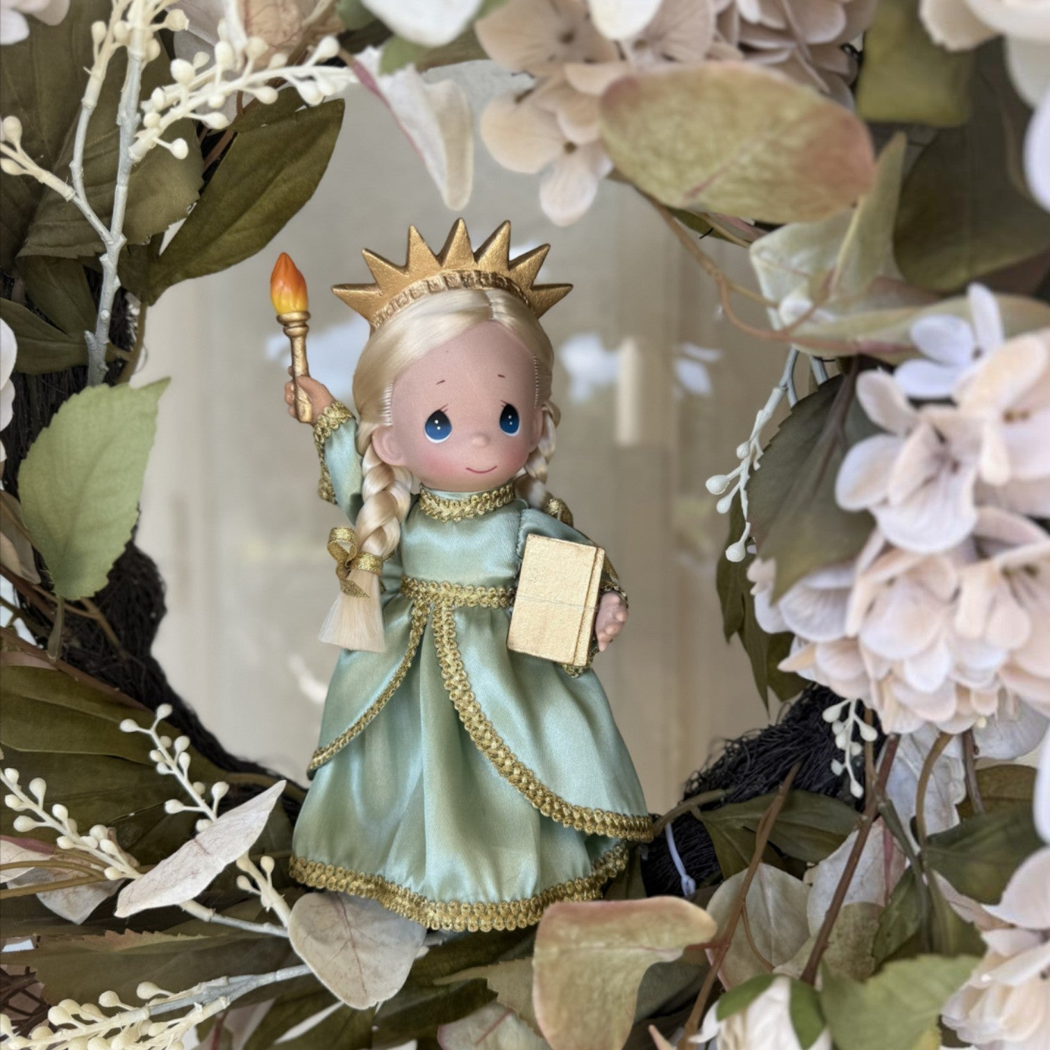 The Doll Maker 9-inch Statue of Liberty doll in a green dress with a gold crown, holding a torch and book