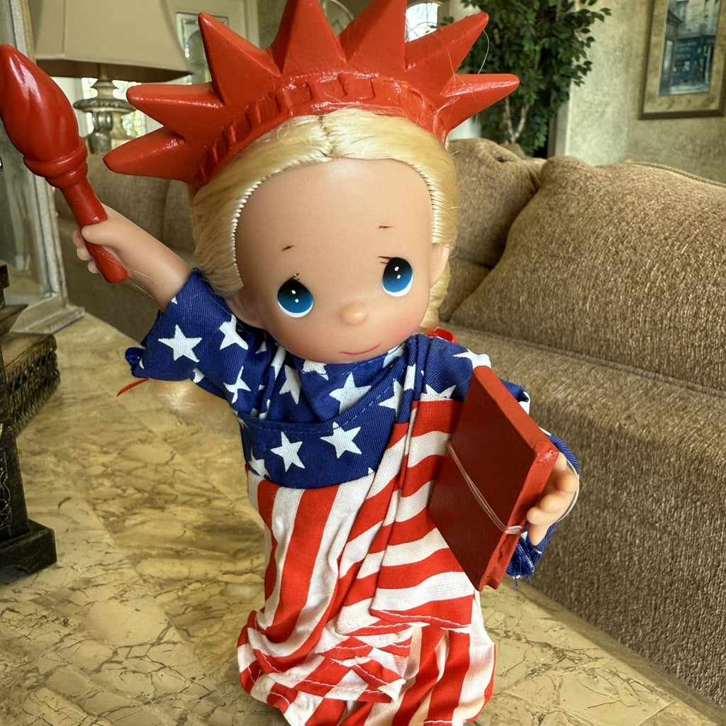 The Doll Maker 7-inch Statue of Liberty vinyl doll with blonde hair, star-spangled robe, torch, and book.
