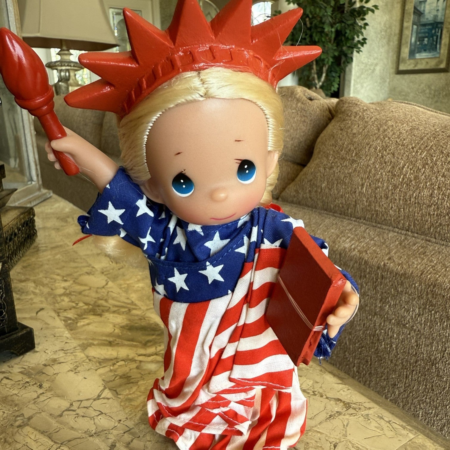 The Doll Maker 7-inch Statue of Liberty vinyl doll with blonde hair, star-spangled robe, torch, and book.