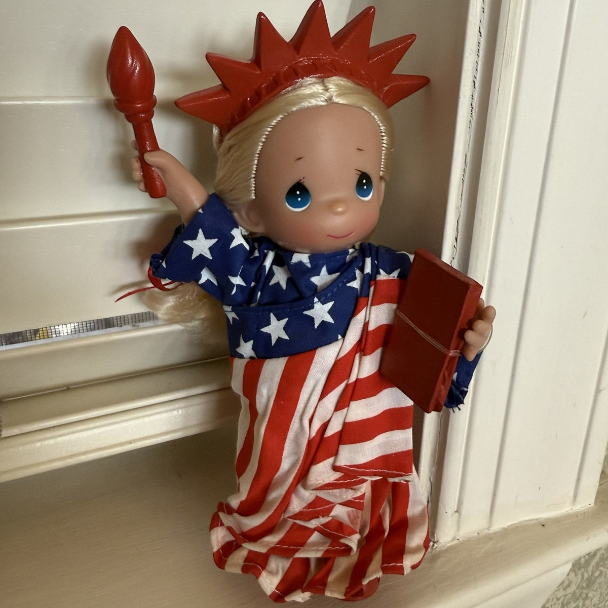 The Doll Maker 7-inch Statue of Liberty vinyl doll wearing a star-spangled banner robe with a red crown and torch.