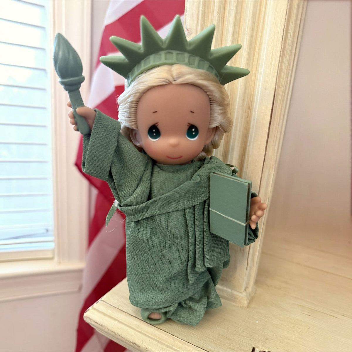 The Doll Maker 7-inch Statue of Liberty vinyl doll featuring iconic crown, torch, and tablet in a green gown.