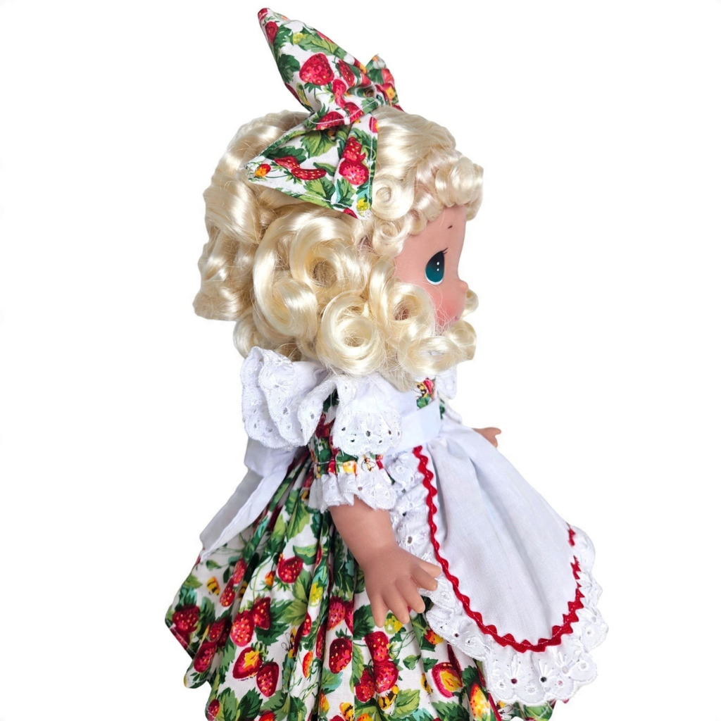 The Doll Maker You’re Berry Sweet 12-inch blonde vinyl doll wearing a strawberry print dress and matching hair bow.