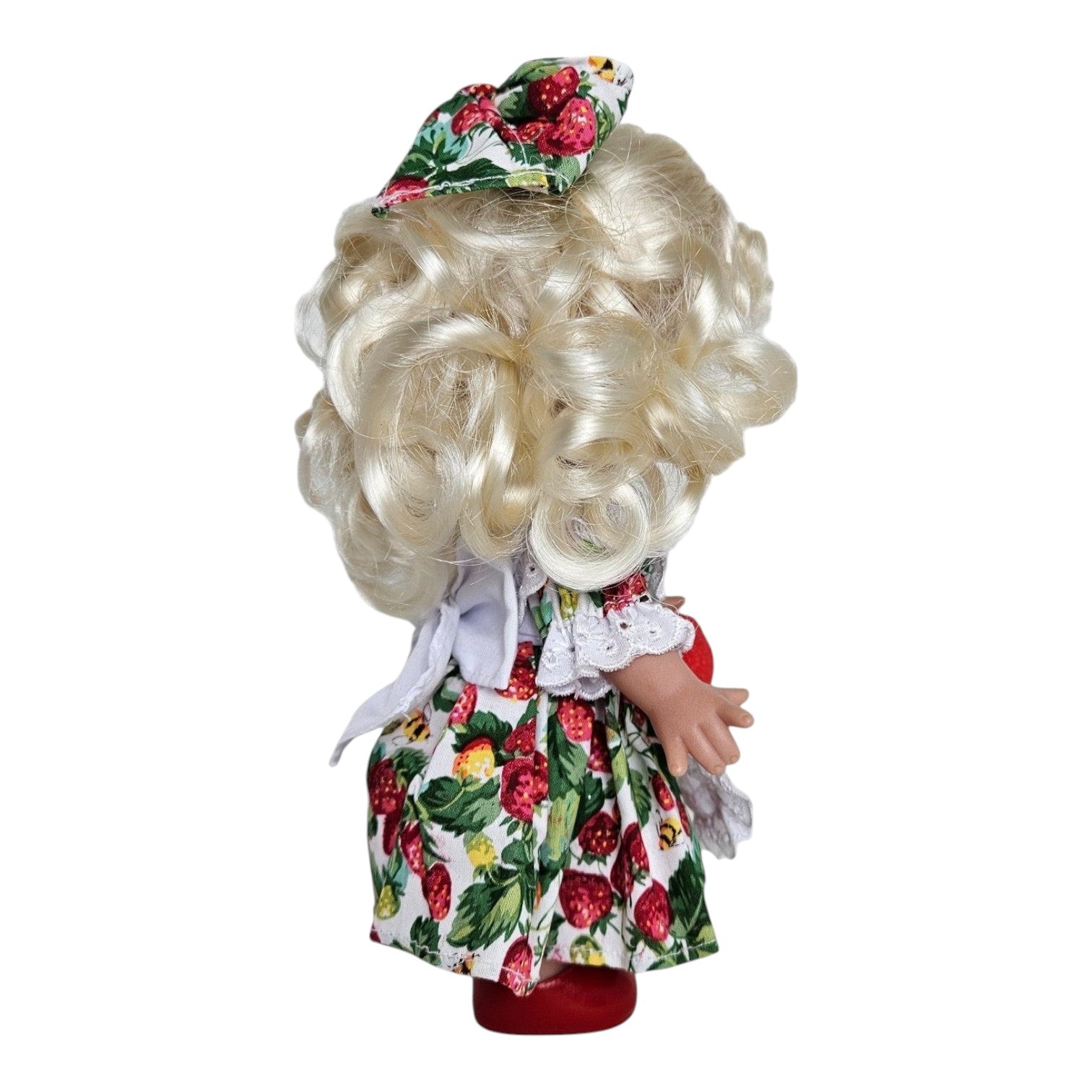Back view of The Doll Maker You’re Berry Sweet 9-inch vinyl doll with blonde curls and strawberry print dress.