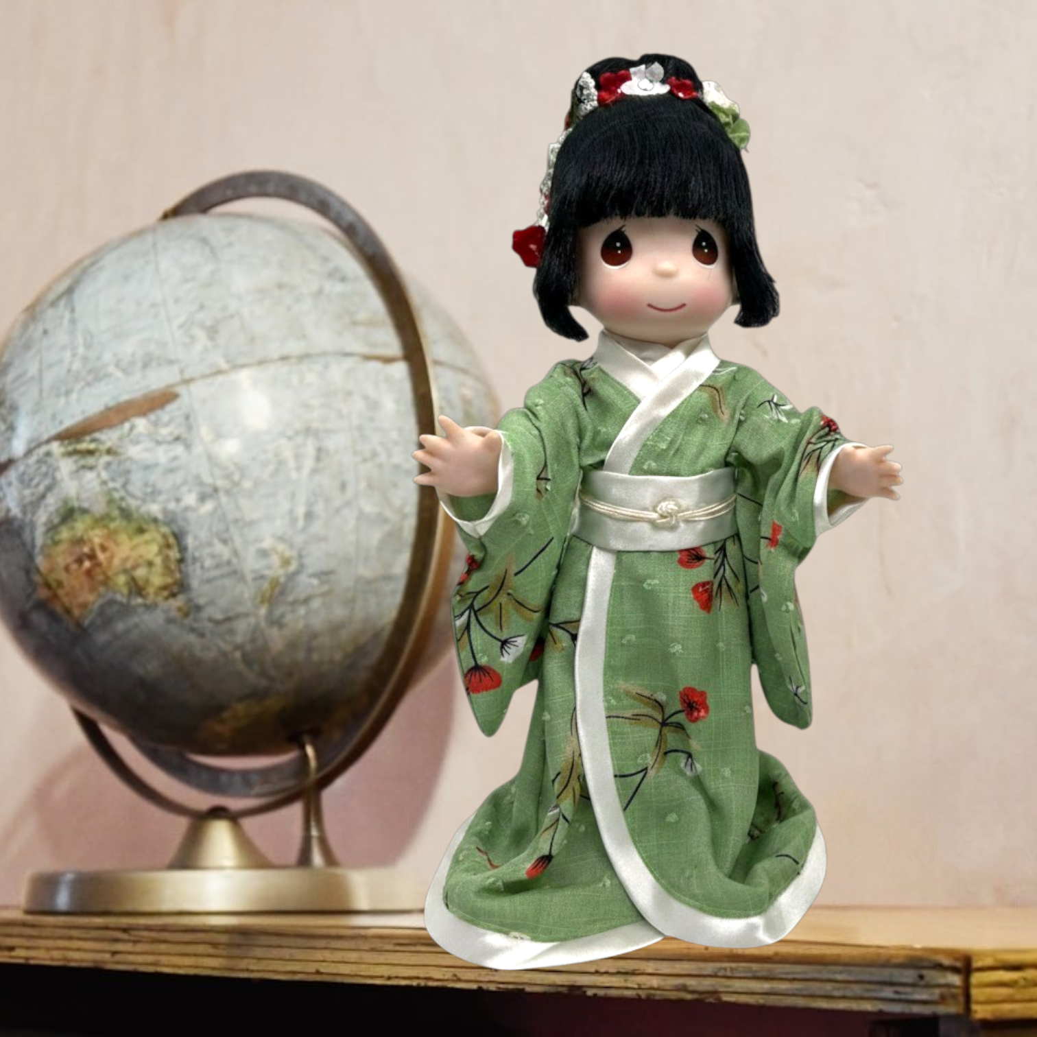 The Doll Maker 12-inch Tomomi doll wearing a green floral kimono with white trim, standing next to a vintage globe.