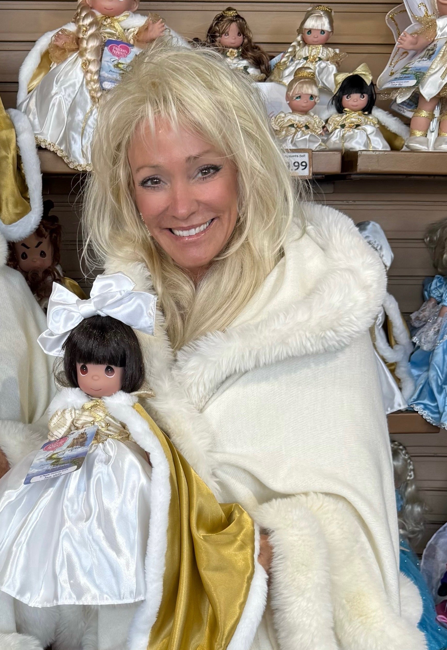 White hooded winter cape with plush fur trim worn by Linda Rick holding a Snow White doll she created