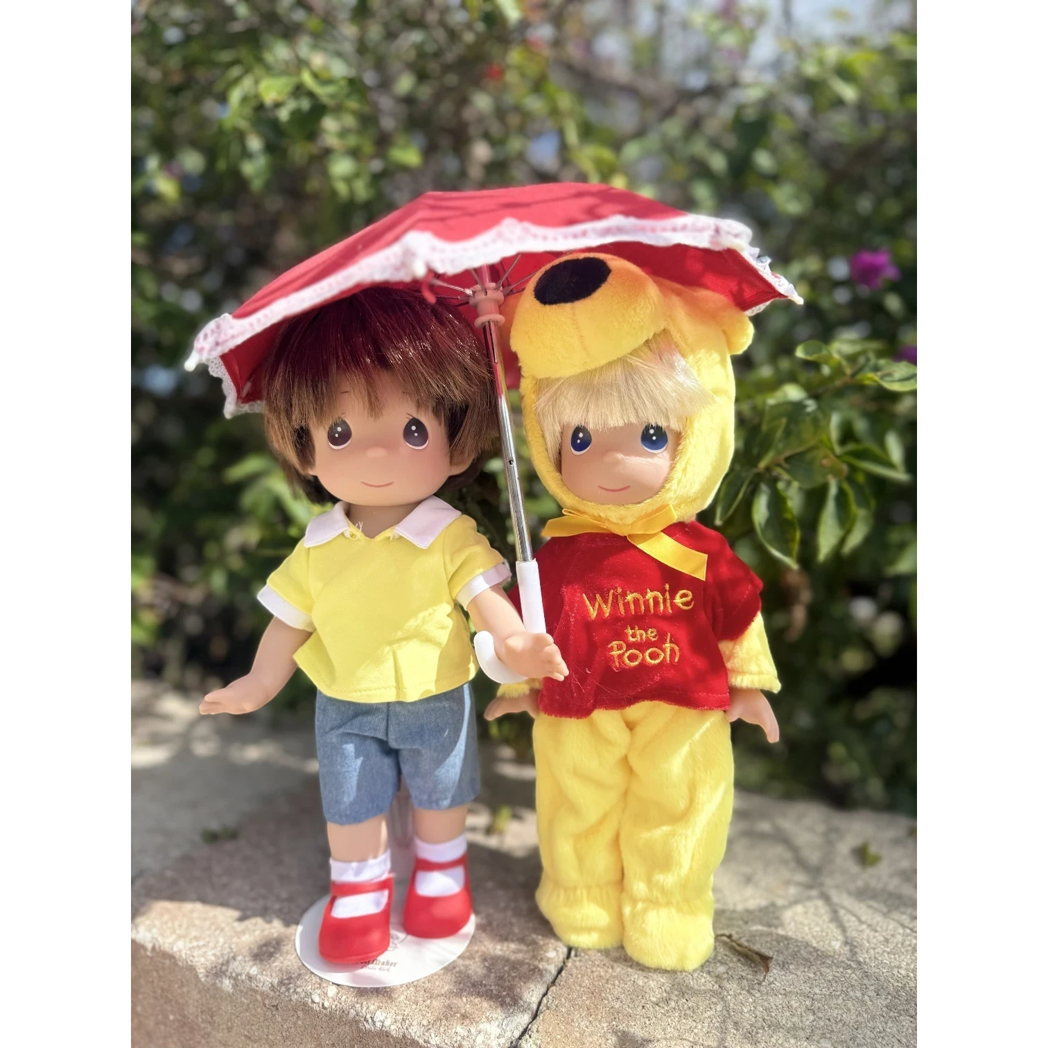 The Doll Maker Winnie the Pooh 12-inch doll wearing a red and yellow bear costume standing next to a boy doll
