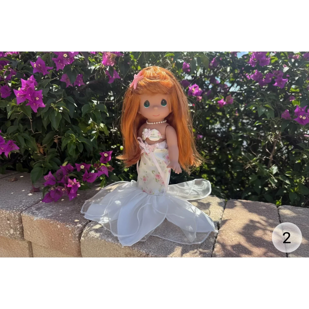The Doll Maker's 12-inch mermaid doll with long auburn hair, wearing a floral print dress and white organza tail.