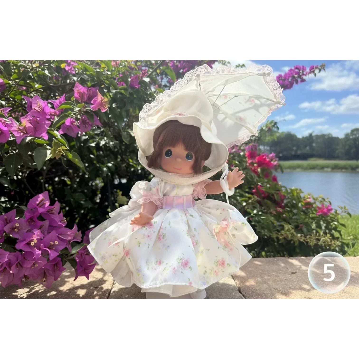 The Doll Maker's 12-inch Spring Bouquets doll in a white floral dress with pink trim and a matching hat and parasol.