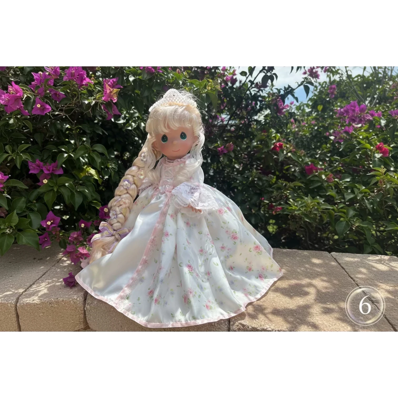The Doll Maker's 12-inch Spring Bouquets doll with blonde braided hair and a white floral dress with pink trim.