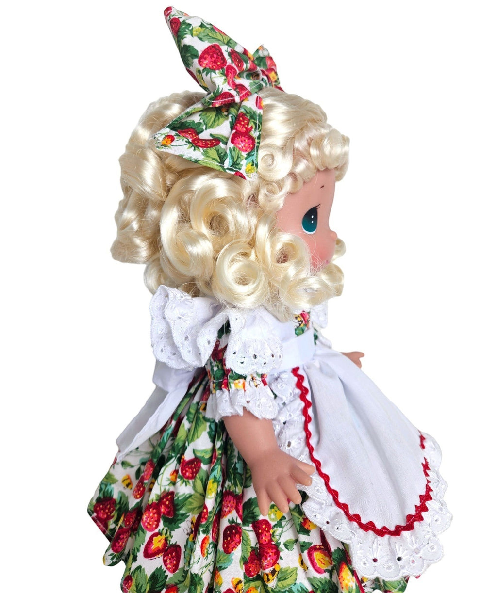 The Doll Maker's "You're Berry Sweet" 12" doll with blonde curly hair, wearing a strawberry print dress and bow. Fabric and vinyl construction.